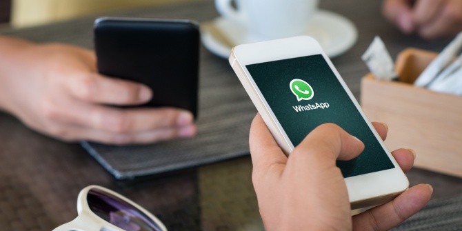 Junge Frau im Cafe sitzend und mit Whatsapp chattend