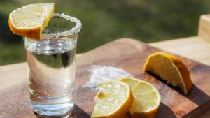 Close-Up Of Tequila Shot With Lemons Slices On Cutting Board